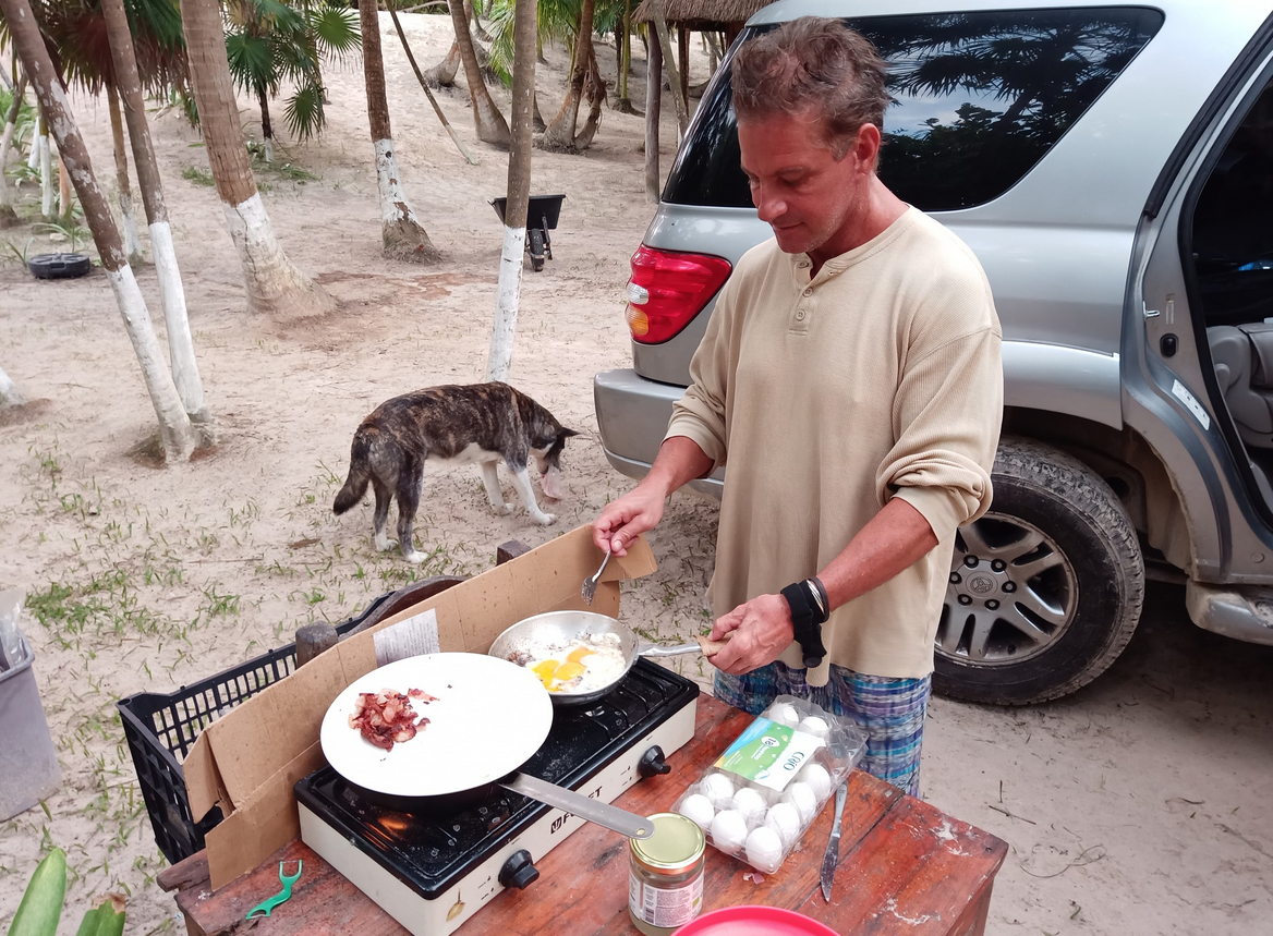 Cooking breakfast on a camp stove outside a tent setup at El Último Maya, Tulum