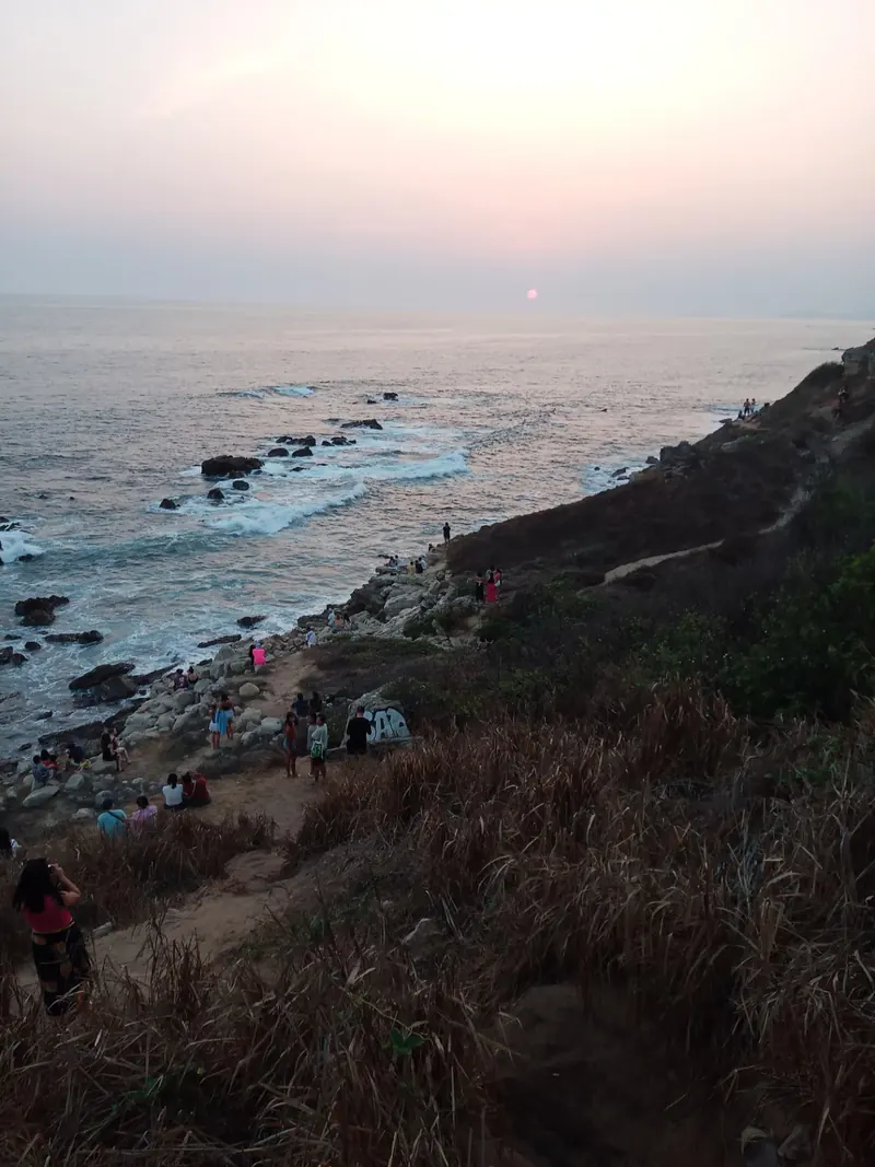 The sun setting in a pink sky over the rocky coastline of Puerto Escondido, Oaxaca