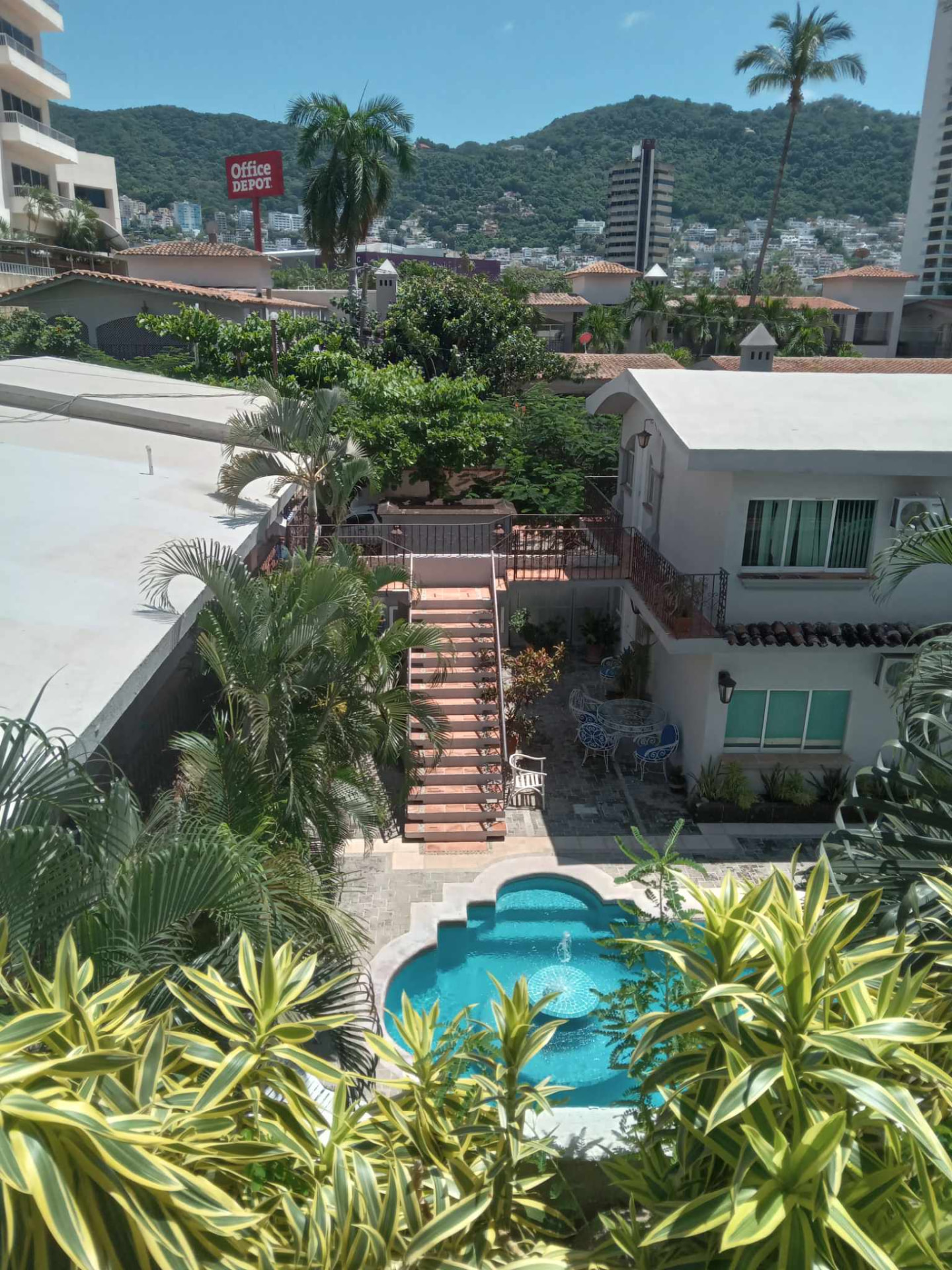Palm trees, a small pool, and terracotta stairs between houses in an Acapulco courtyard before Hurricane Otis